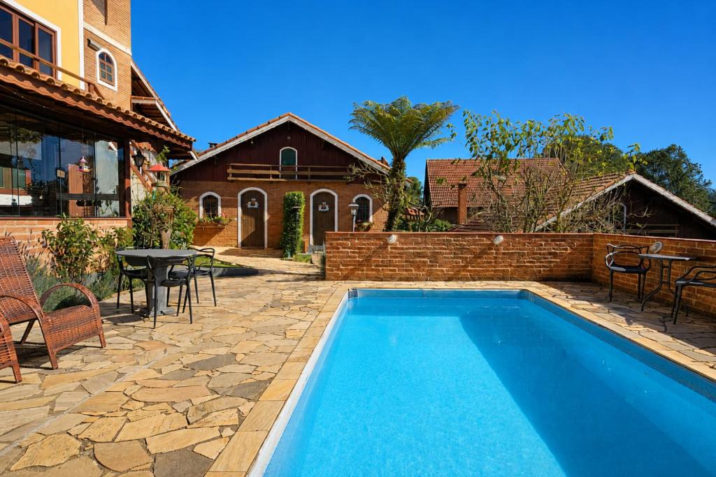 a swimming pool in a backyard with a table and chairs at Pousada Palma Chalés in Monte Verde