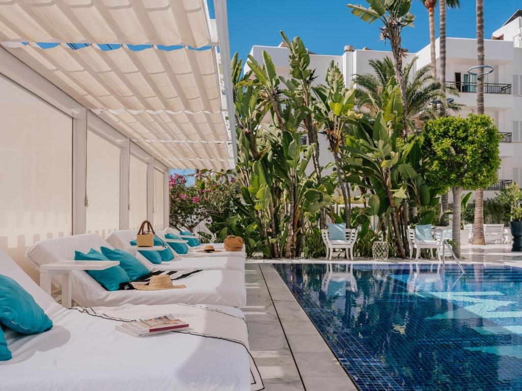 a hotel pool with white beds and blue pillows at MiM Ibiza member of Meliá Collection in Ibiza Town