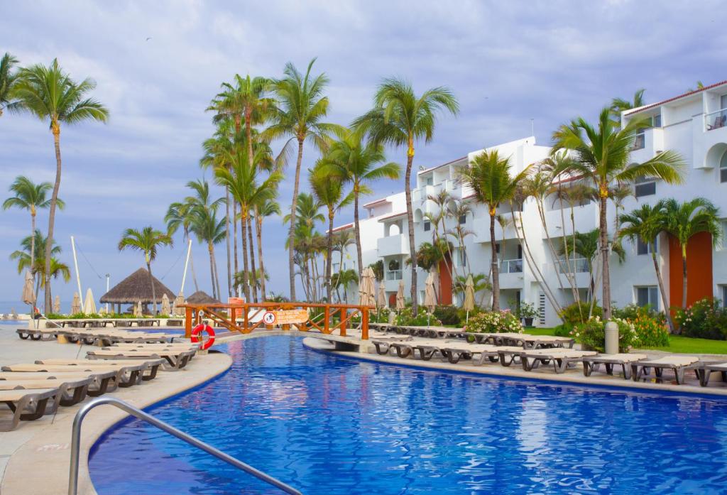 a resort swimming pool with chaise lounges and palm trees at Marival Emotions Resort & Suites - All Inclusive in Nuevo Vallarta 