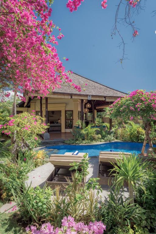 a resort with a swimming pool and pink flowers at Villa KaRo Pemuteran in Pemuteran