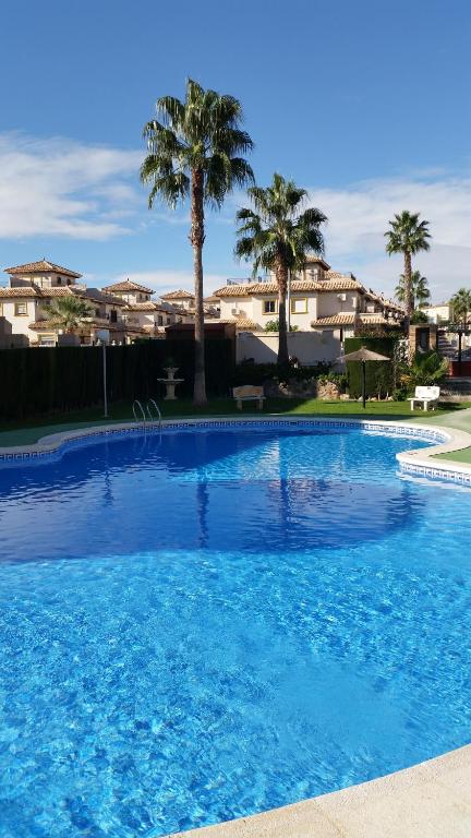 a large blue swimming pool with palm trees and houses at Aalia villa in Villacosta