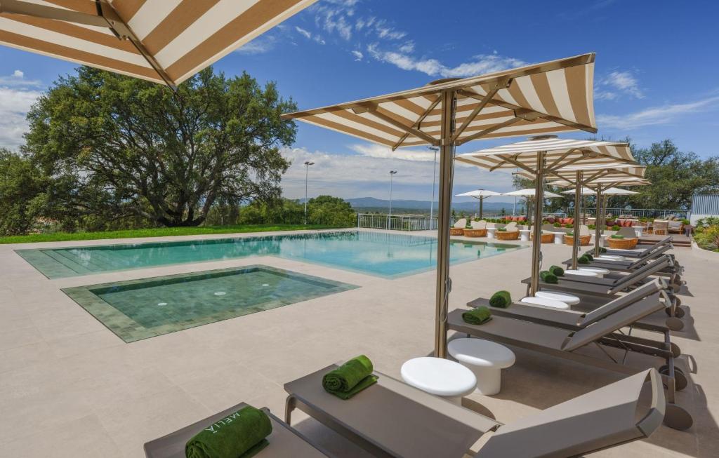 a pool at a resort with lounge chairs and umbrellas at Meliá Castelo Branco in Castelo Branco