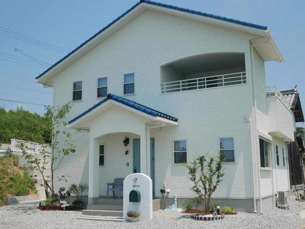 ein weißes Haus mit blauem Dach in der Unterkunft アオイカゼ in Awaji