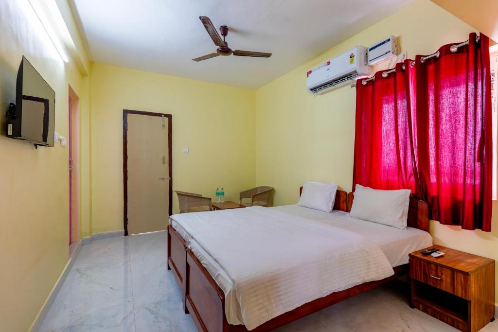 a bedroom with a large bed with red curtains at Subham Residency in Chennai