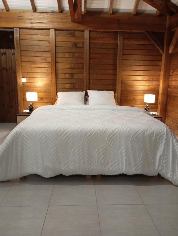 a bedroom with a white bed with wooden walls at Lodge de Charme Vue Imprenable in Le Robert