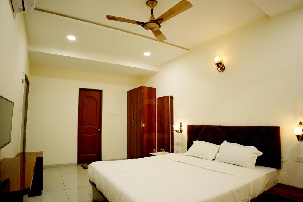 a bedroom with a large white bed with a ceiling fan at Hotel green hills in Waki