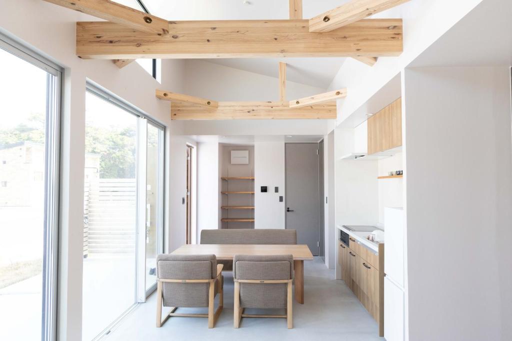 a kitchen with a table and chairs and windows at ウミチカ in Minamiboso