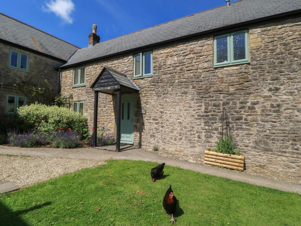 two chickens standing in front of a brick house at Dale Barton in Wells