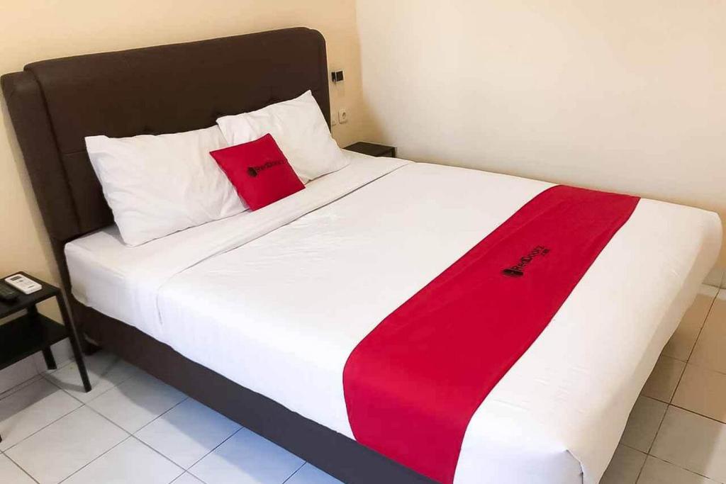 a large white bed with a red blanket on it at RedDoorz @ Pavilion Residence Cikarang in Jakarta