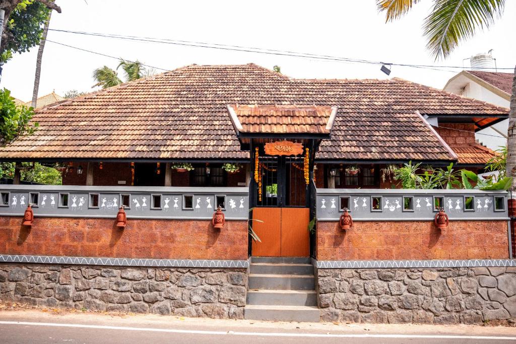 a building with an orange door on a stone wall at Illam By Santhi in Varkala