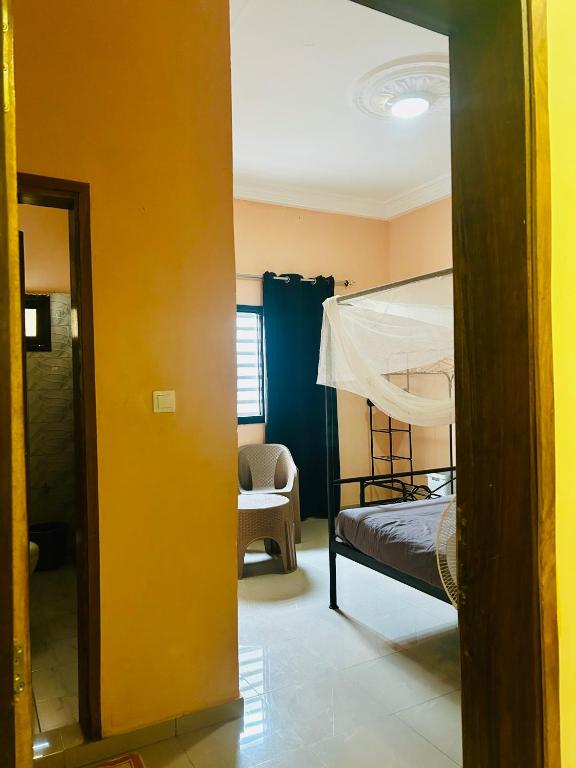 a room with a bed and a bedroom with a mirror at Chambre avec salle d eau privée in Mbour