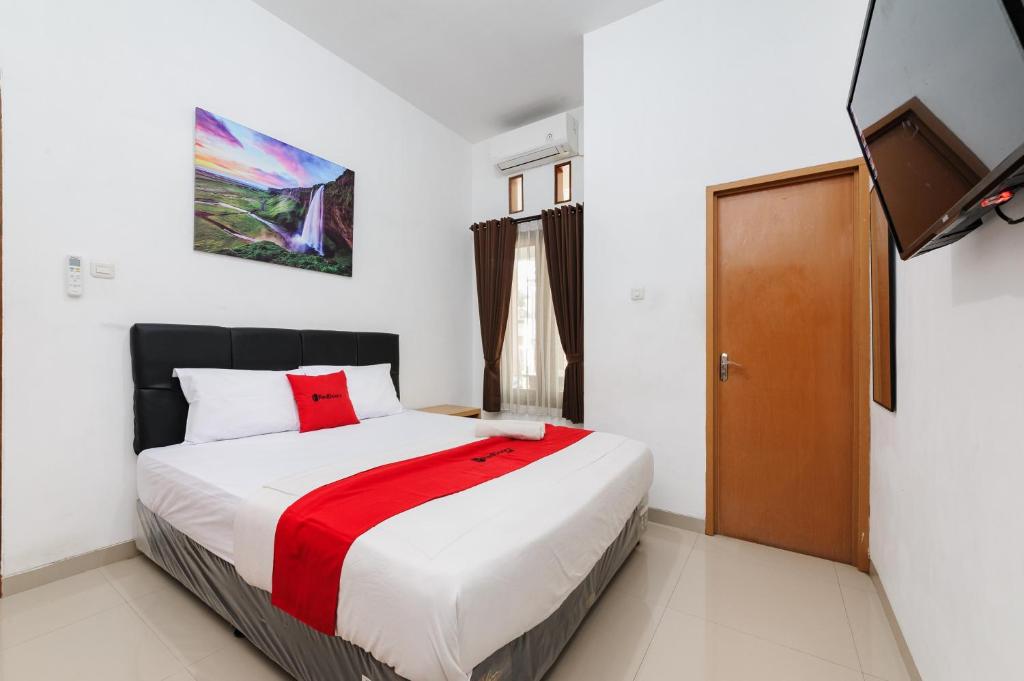 a bedroom with a bed and a flat screen tv at RedDoorz @ Jalan Danau Limboto in Malang