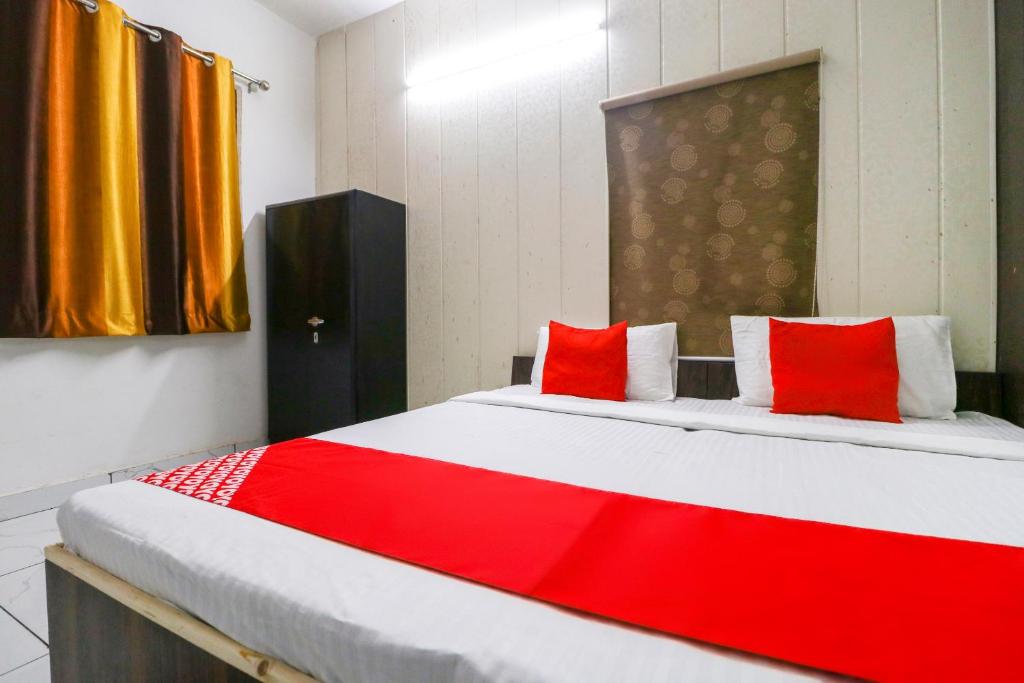 a bedroom with a large bed with red pillows at Hotel O Sky Garden in Ludhiana