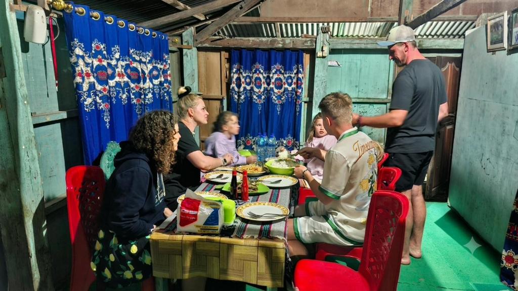 a group of people sitting around a table eating at Sunrise Komodo Homestay in Komodo