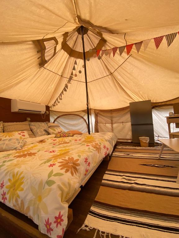 a bedroom with a bed in a tent at Muribushi-PLUS Gramping TENT in Motobu