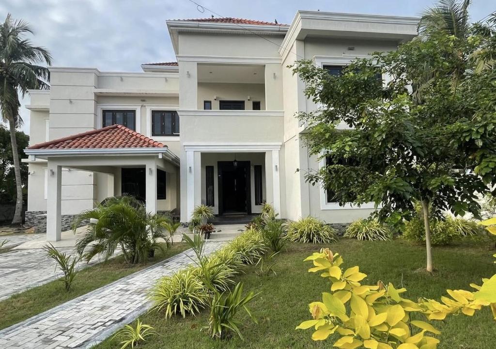 a large white house with a garden in front of it at Palm Breeze Villa in Mannar