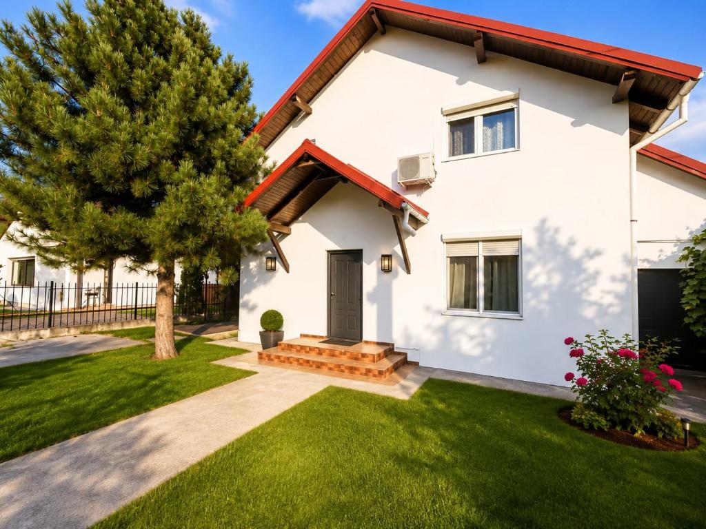 a white house with a tree and grass at Vila Ioana in Ştefăneşti