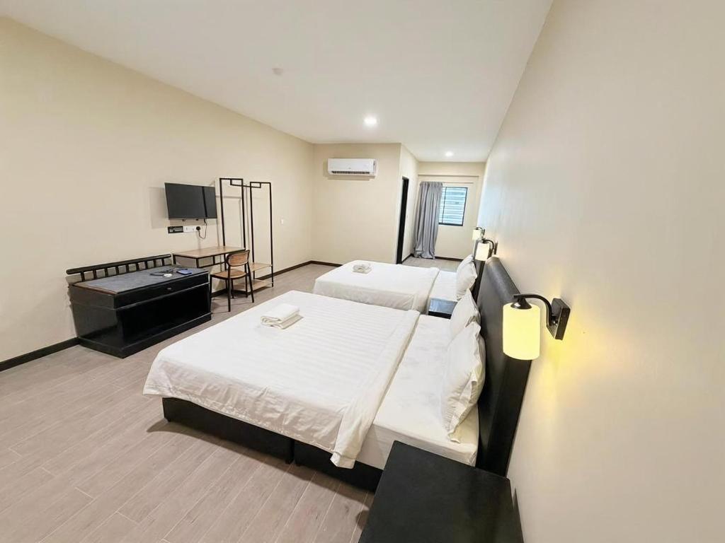 a hotel room with two beds and a flat screen tv at Pertama Lodge in Tawau