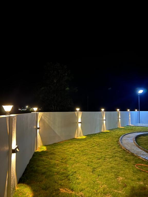 a fence with lights on the grass at night at Villa Hayfa in Kuala Kerai