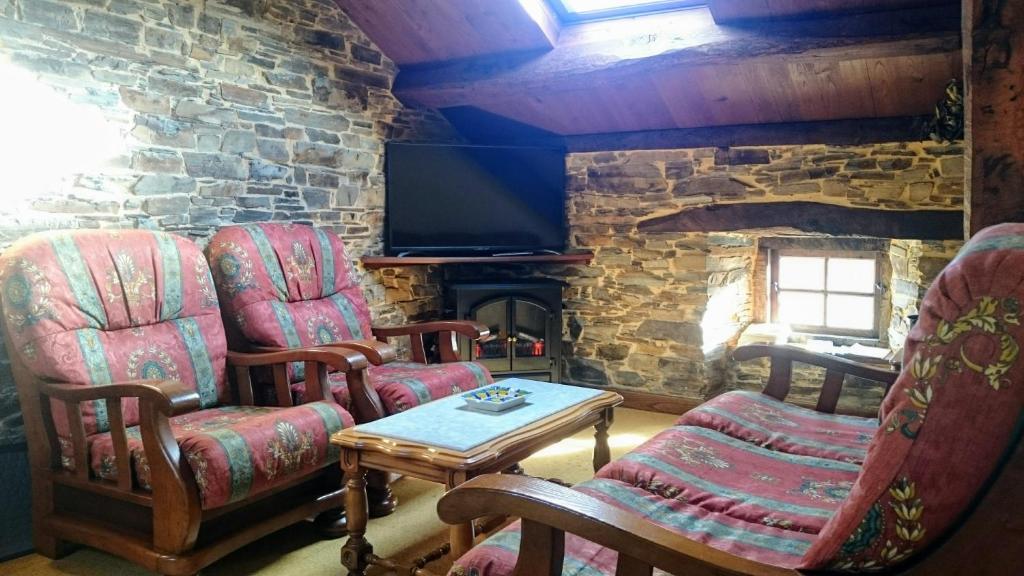 a living room with two chairs and a stone fireplace at Apartamentos Rurales Vega de Llan in Taramundi