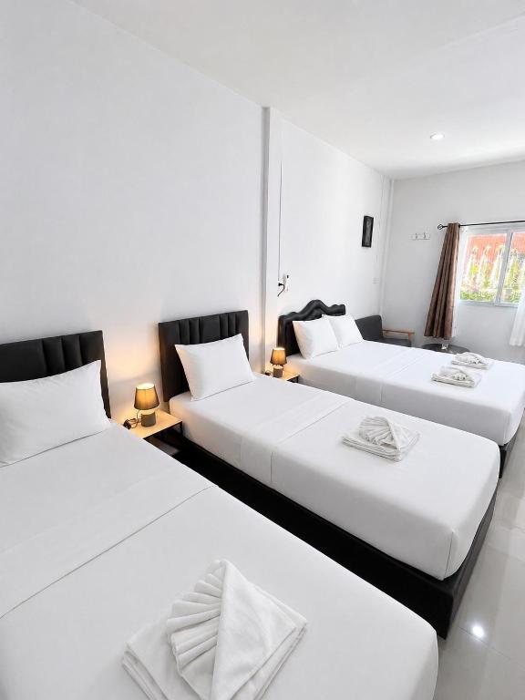 three beds in a room with white walls at Yada House Cozy Place in Nai Yang Beach