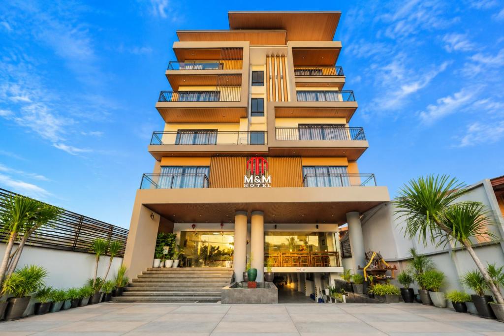 a tall building with palm trees in front of it at M&M Hotel in Vang Vieng