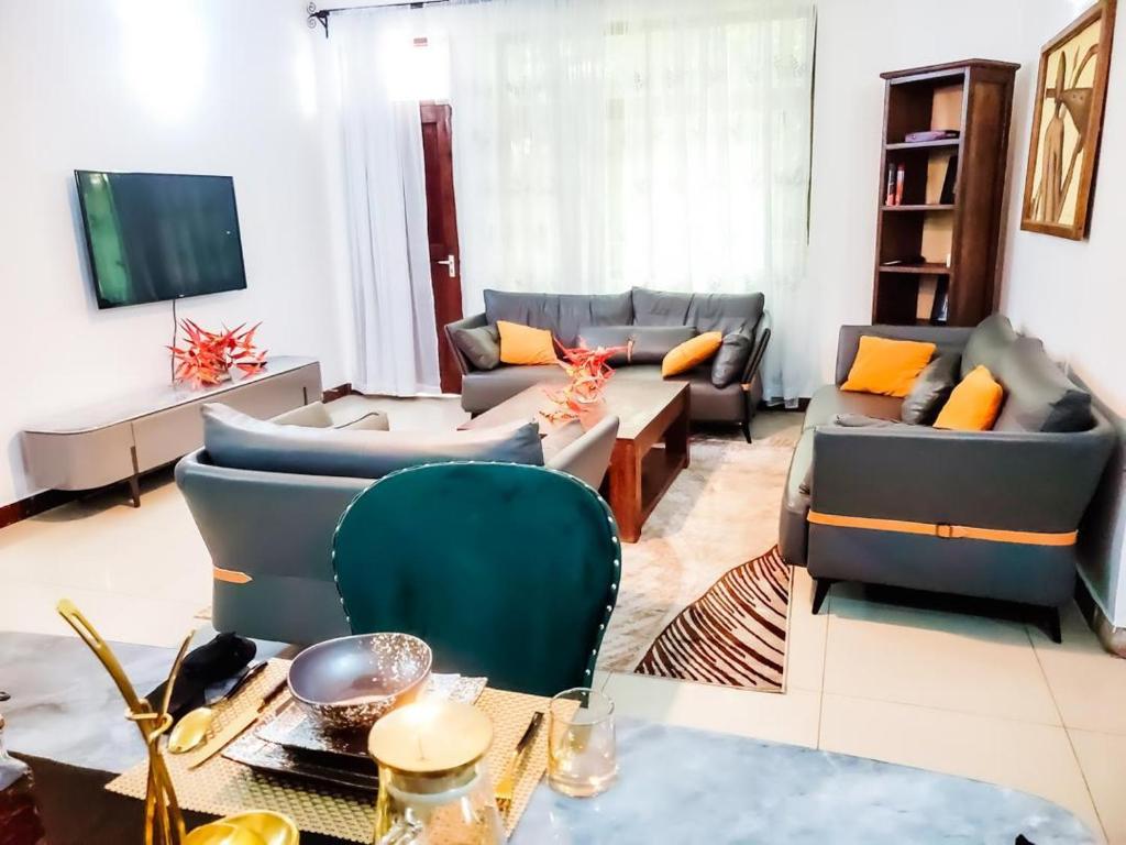 a living room with couches and a tv at AWESOME HOME's in Arusha
