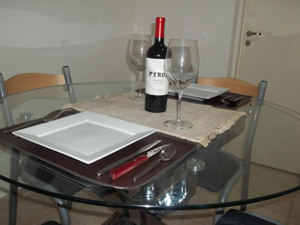 - une table en verre avec une bouteille de vin et 2 verres dans l'établissement Apartamento Pichincha Rosario, à Rosario