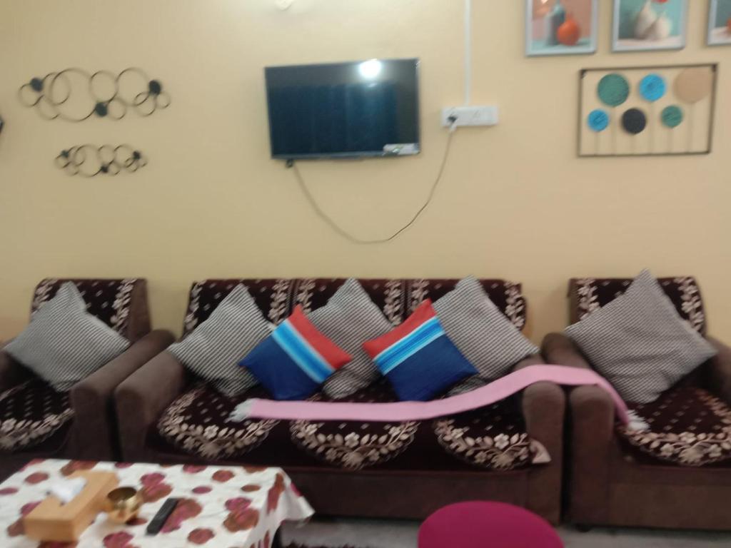 a living room with a couch with pillows and a tv at Two BHK and Four BHK Fully Furnished Flats for 1 to 13 guests - Near Charminar and Salar Jung Museum in Hyderabad