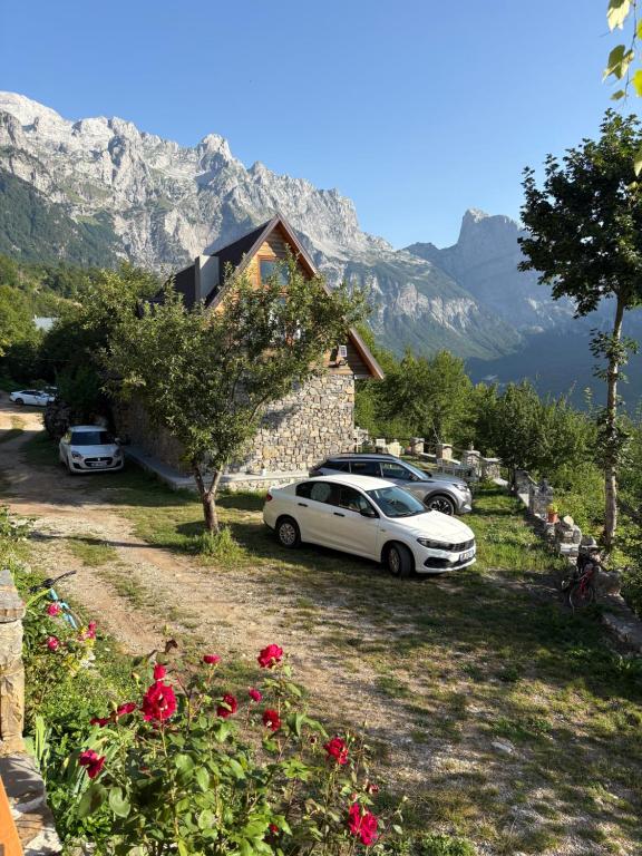 a white car parked in front of a house with mountains at Nini Guesthouse Theth in Theth