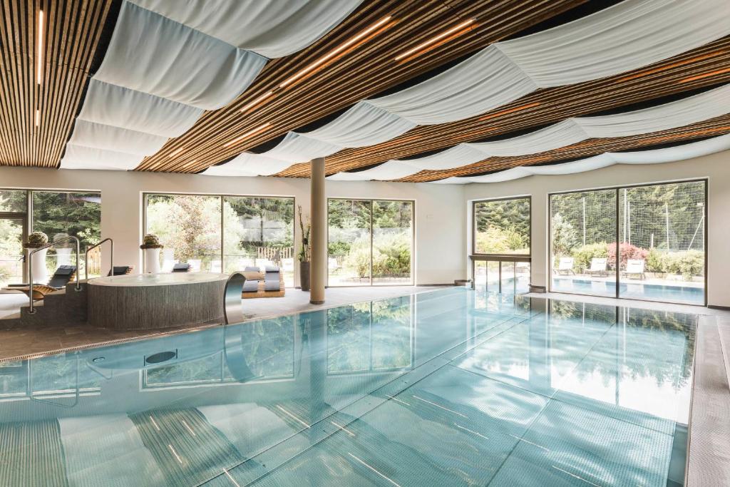 an indoor swimming pool with a large ceiling and windows at Sporthotel Zoll in Vipiteno