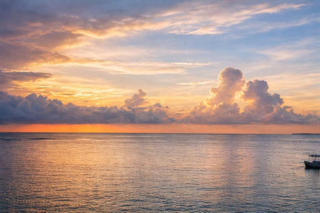 a boat in the ocean with a sunset in the background at Backpackers inn Hostel in Trincomalee