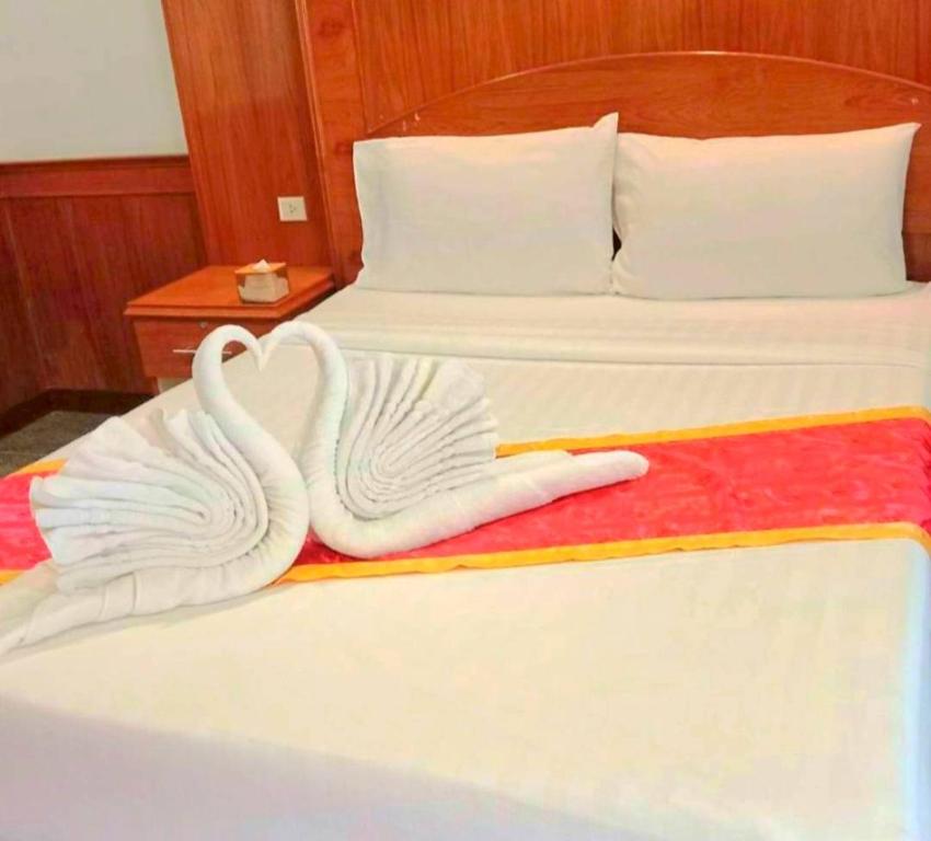 two swans made out of towels on a bed at ปราสาทรีสอร์ท in Prasat