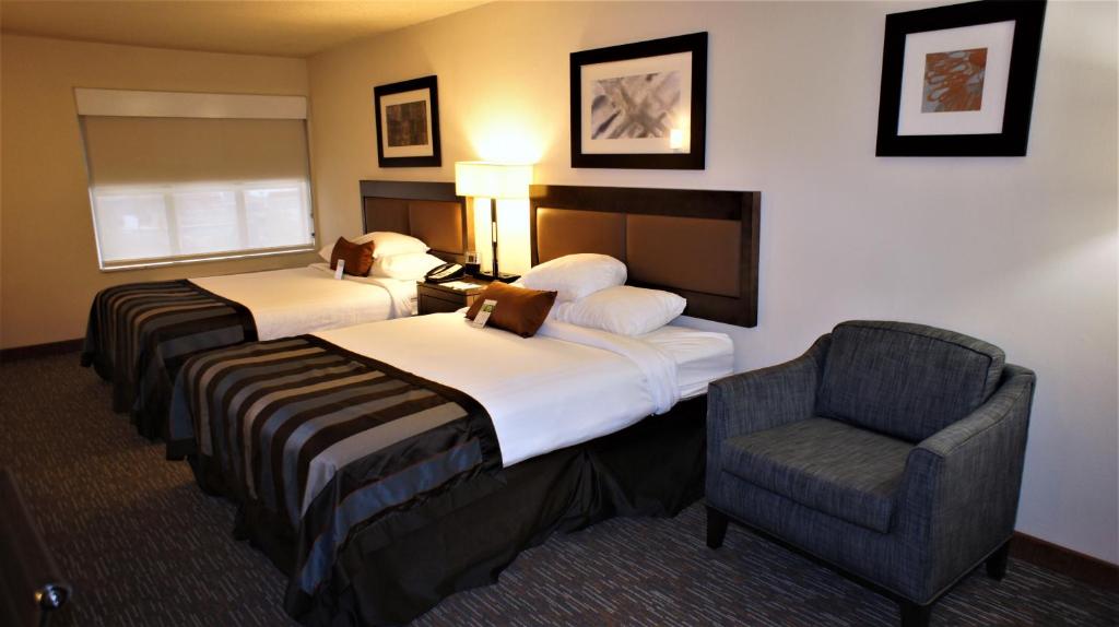 a hotel room with two beds and a chair at Wingate by Wyndham - Chattanooga in Chattanooga