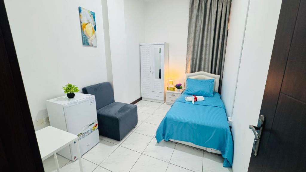 a small bedroom with a blue bed and a chair at Capital View in Abu Dhabi