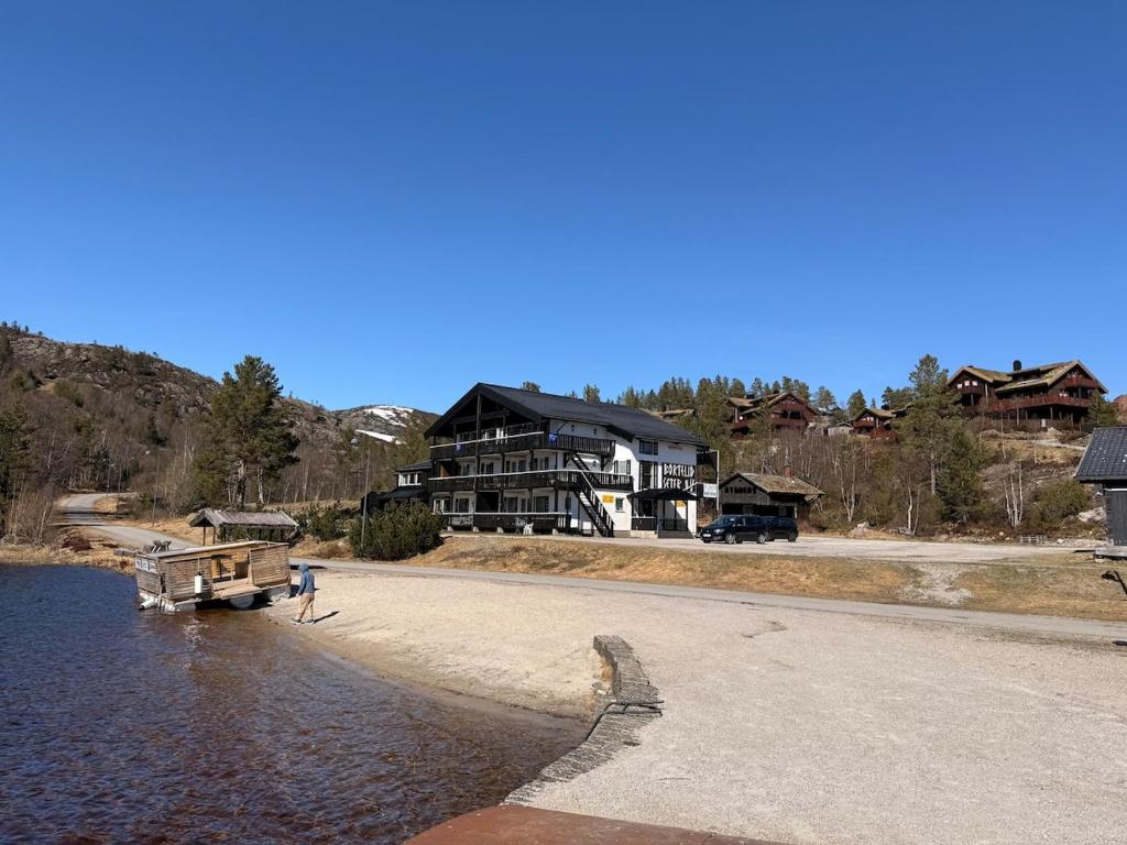 a person walking on the shore of a lake with a house at Bortelidseter in Åseral