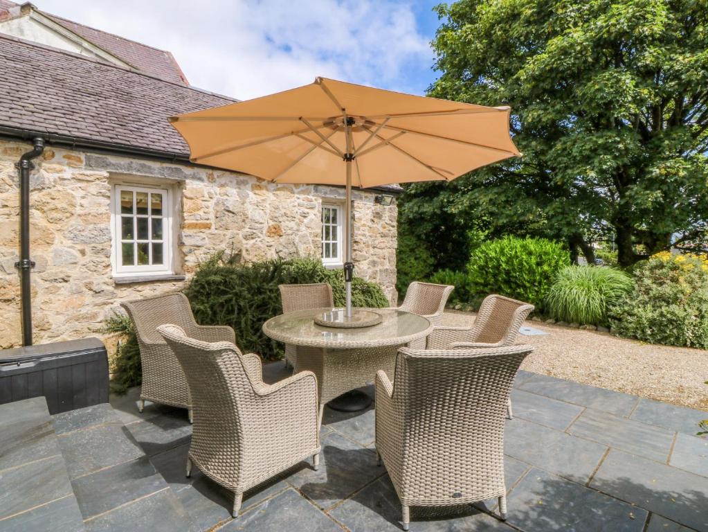 a patio with a table and chairs and an umbrella at Tyddyn Iolyn in Benllech