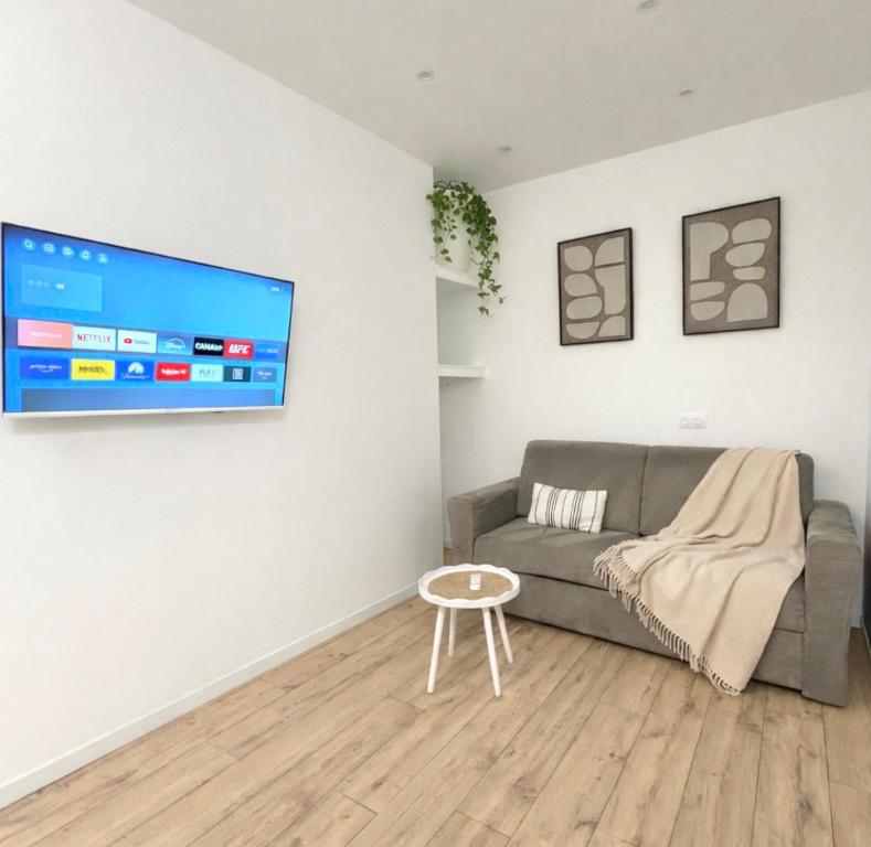 a living room with a couch and a tv on a wall at Studio Parking privé in Guéret