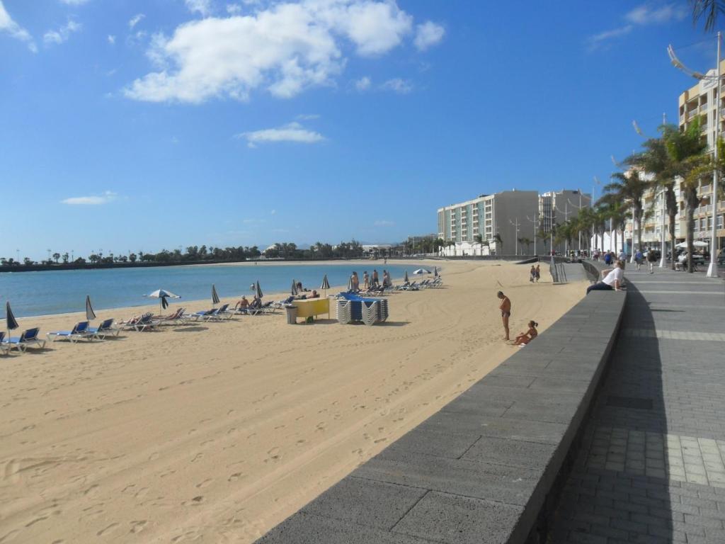 a beach with a group of people sitting on the sand at Aguilon in Arrecife