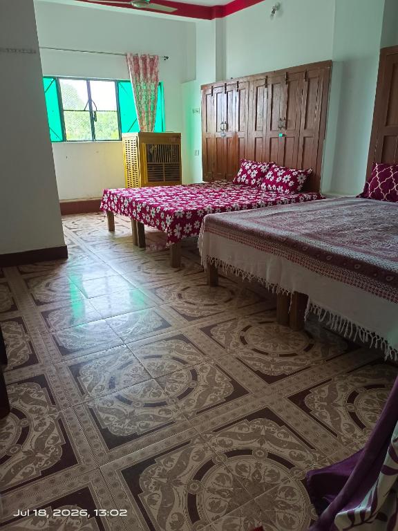 a bedroom with two beds and a floor with a rug at Shri chitrakoot homestay in Chitrakoot