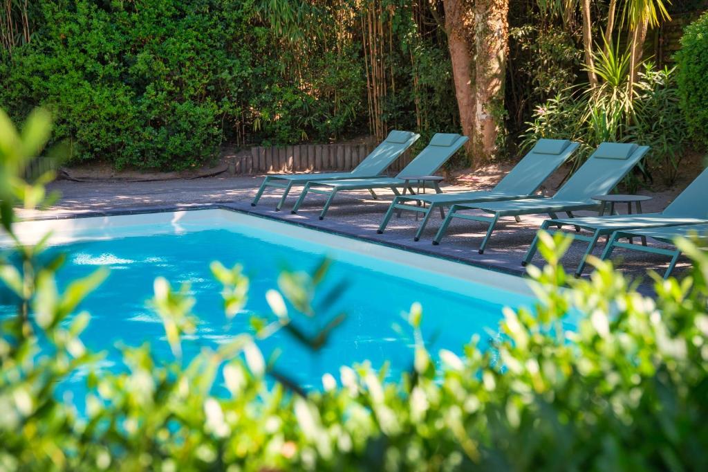 a group of lounge chairs next to a swimming pool at Hôtel Villa Flornoy Pornichet Baie de la Baule in Pornichet