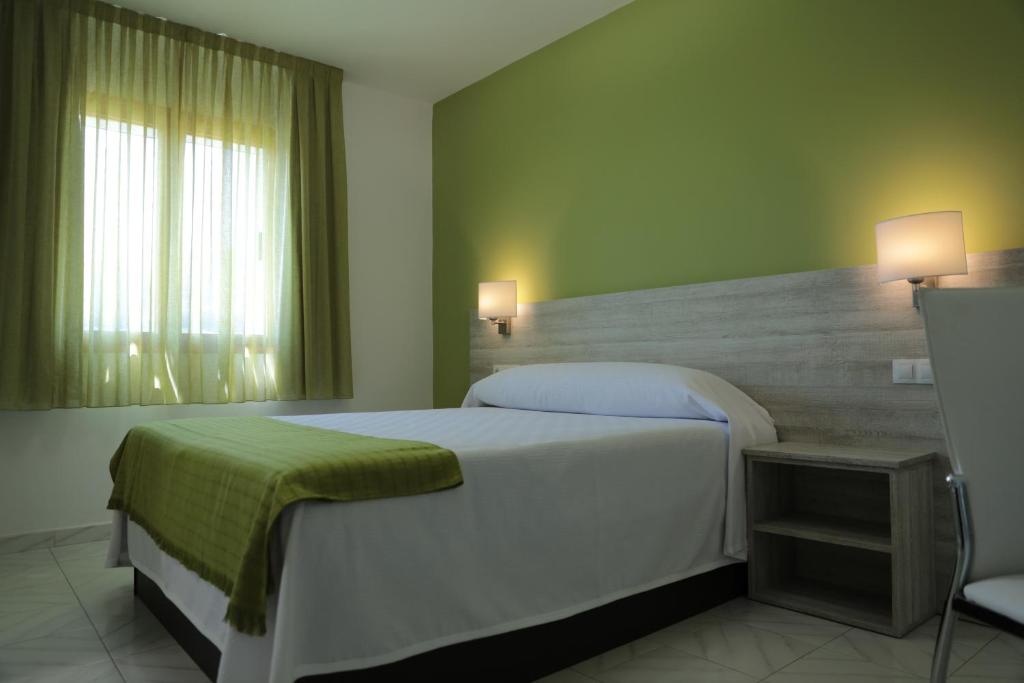 Un dormitorio con una gran cama blanca y una ventana en Hotel Playa de las Catedrales, en Reinante