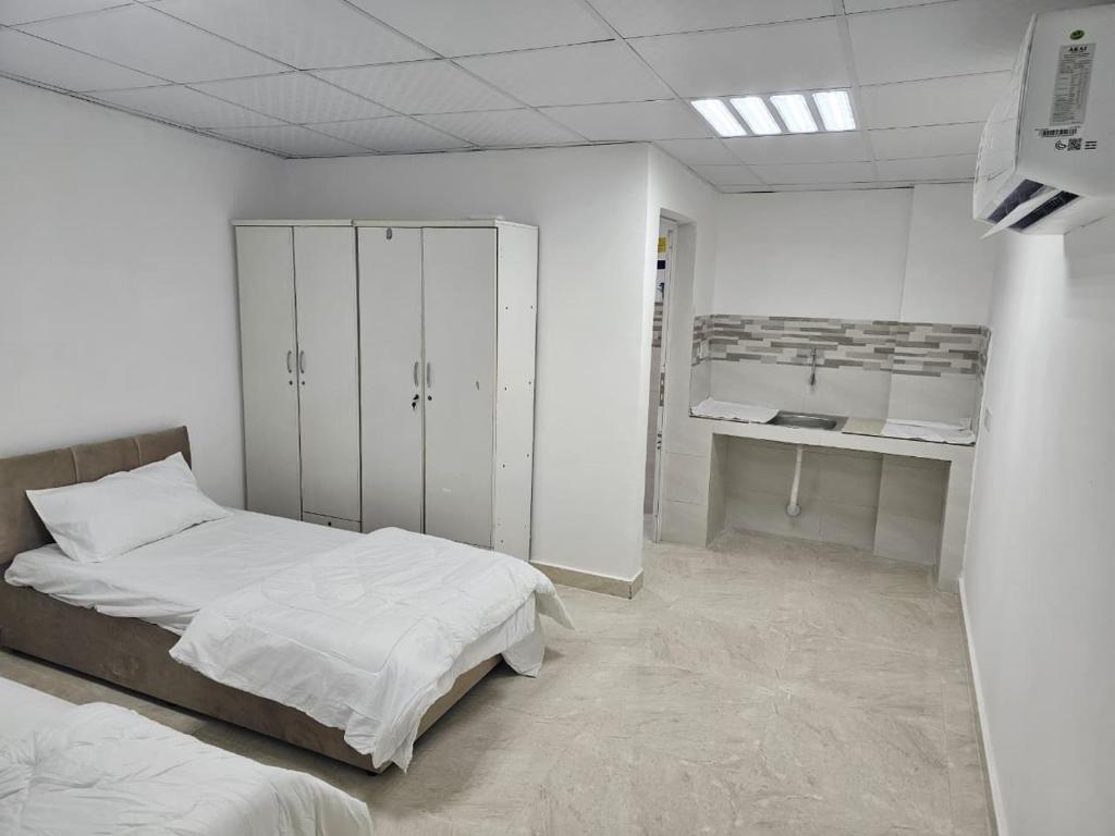 a white room with two beds and a cabinet at غرف شباب عوقد in Salalah