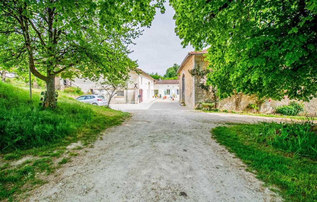 a dirt road in a village with trees and buildings at Harmant Gîte Au Calme in Saint-Maigrin