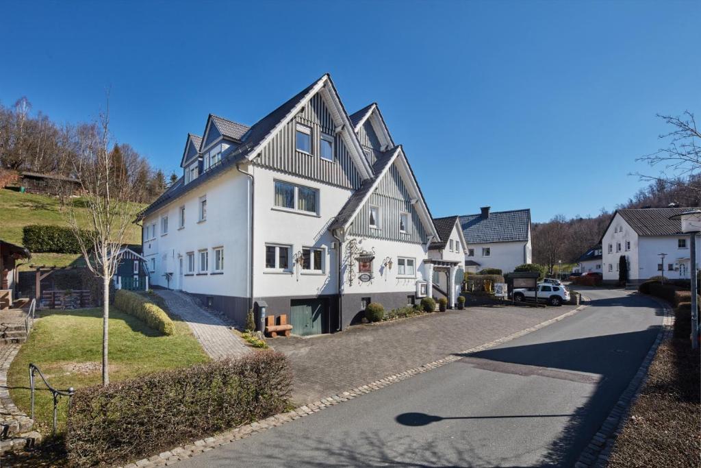 a large white house on a street at Püttmanns Dorfhotel in Olpe