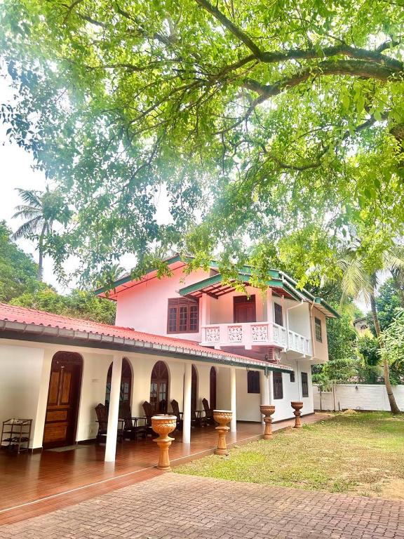 a pink and white house with a balcony at Lion Isle Residence in Anuradhapura