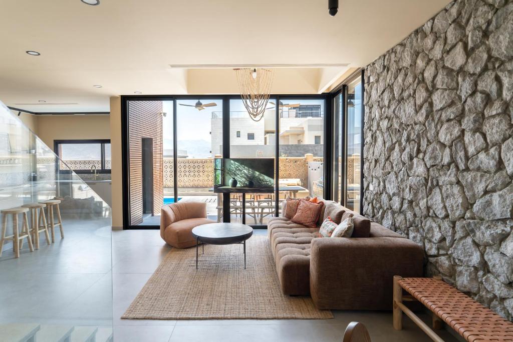 a living room with a couch and a stone wall at Villa Lum - BY Harim in Eilat