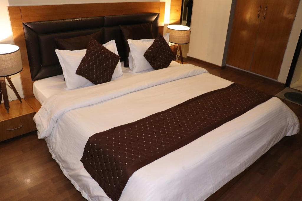 a bedroom with a large bed with white sheets and pillows at Hotel centrum in Roorkee