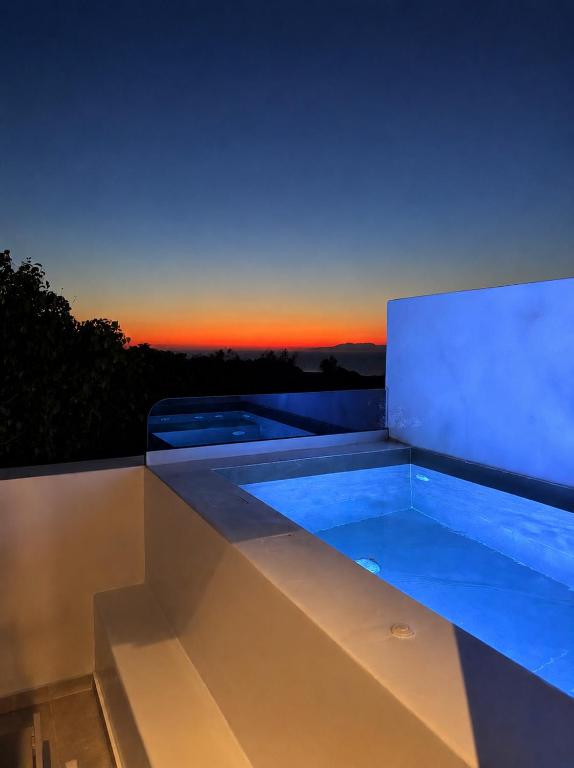 a large swimming pool with a sunset in the background at Acanthus Oia - Suites With Private Hot Tub in Oia