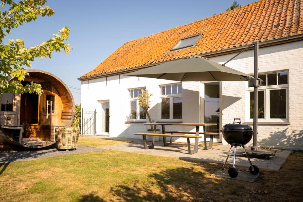 a grill and an umbrella next to a house at 't Boshuisje in Poperinge